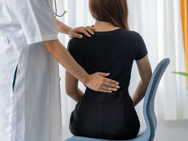 A woman is treated for a sore back by a physiotherapist. 