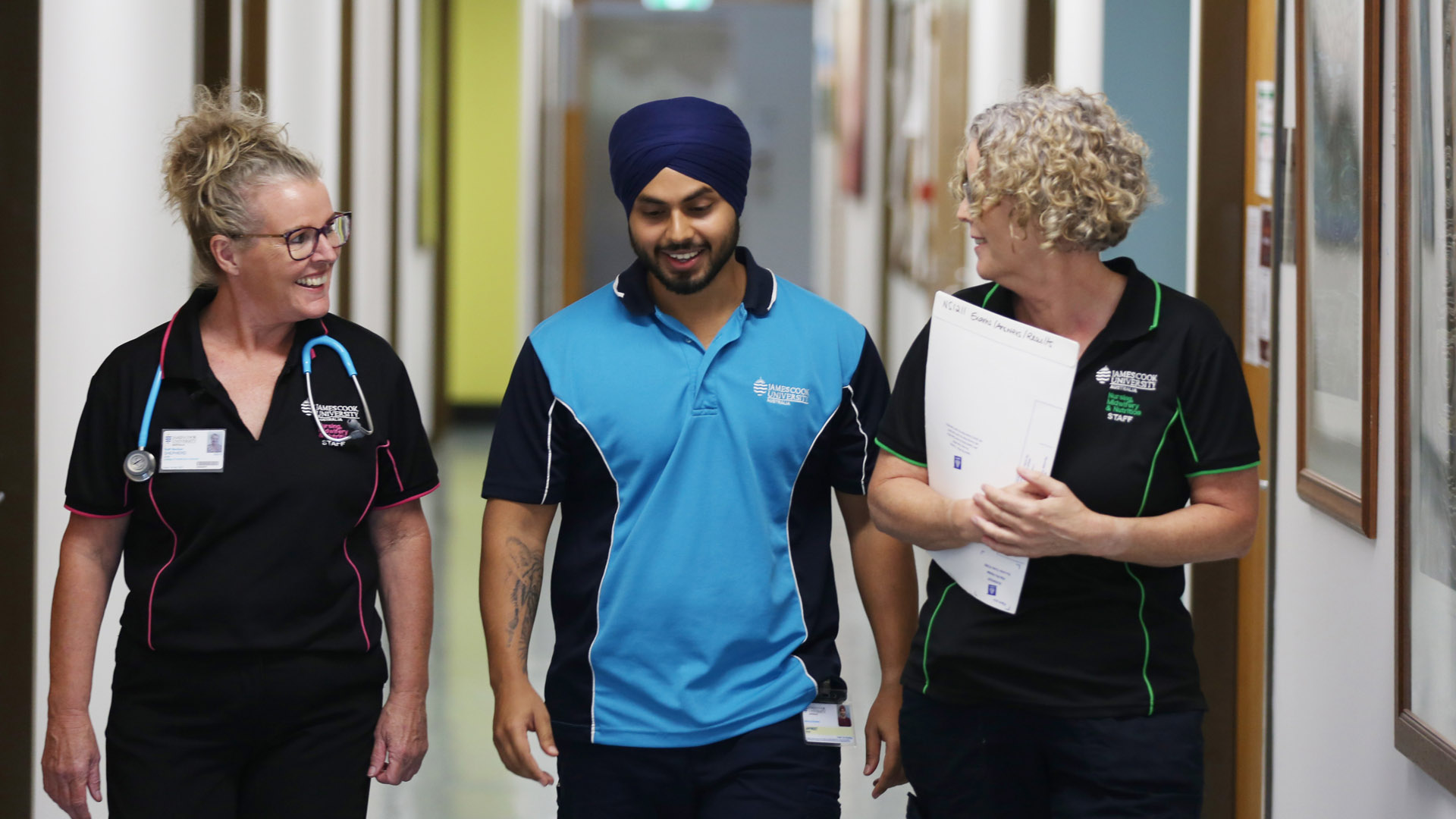 Two James Cook University instructors walk alongside a JCU Nursing student in the halls of a hospital. 