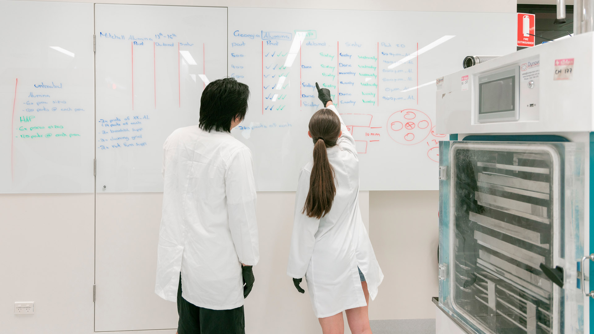 JCU students use a whiteboard for planning out their work in a laboratory on campus. 